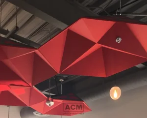 Geometric red acoustic ceiling panels suspended in a modern commercial space